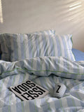 Striped bedding with pillows and a card on a bed
