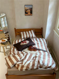 Bedroom with a bed featuring striped bedding and a guitar, with a painting on the wall.