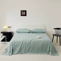 Bedroom with a bed covered in light green bedding, nightstands, and a chair.