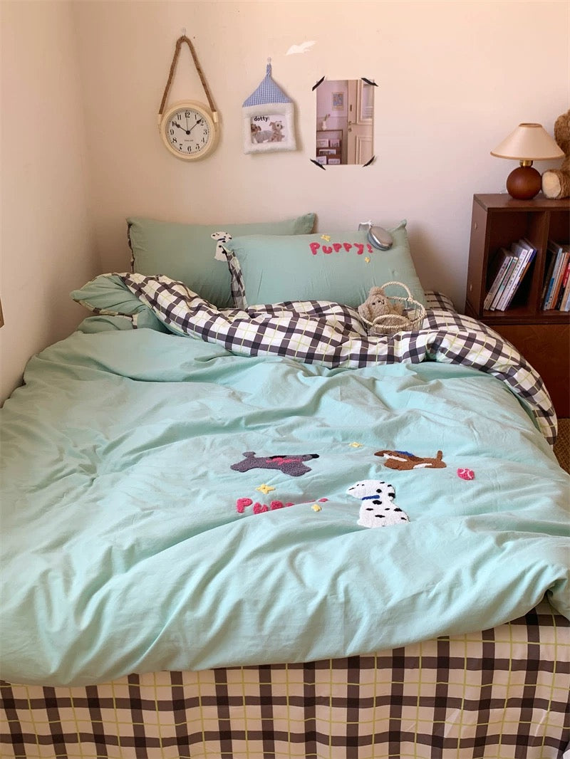 Bed with light blue bedding and checkered blanket, surrounded by decorative items on a shelf.