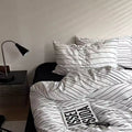 Bed with striped bedding and a lamp on a nightstand in a bedroom.