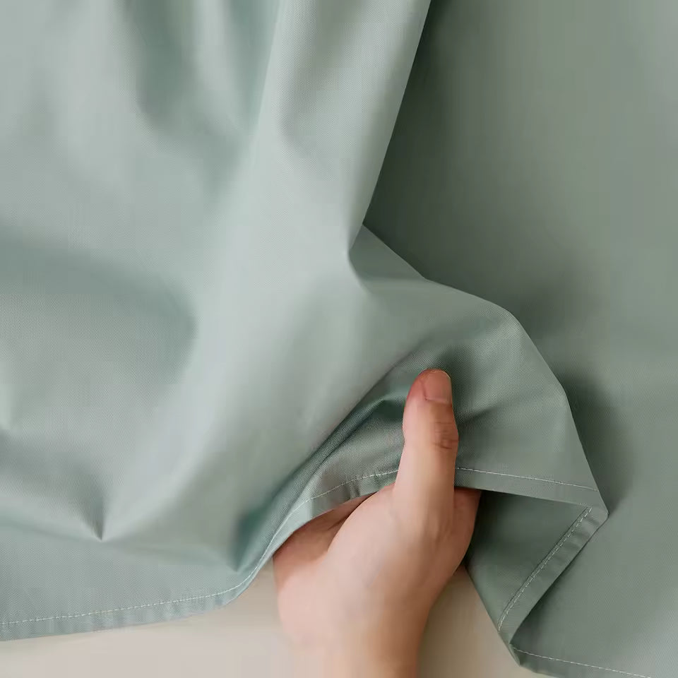 Hand holding green fabric with a neutral background
