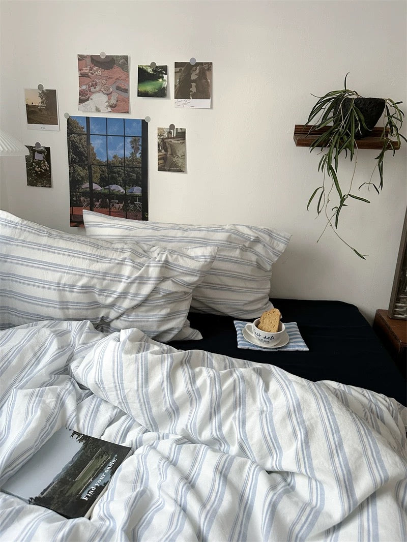 Bedroom with striped bedding, photos on the wall, and a plant.
