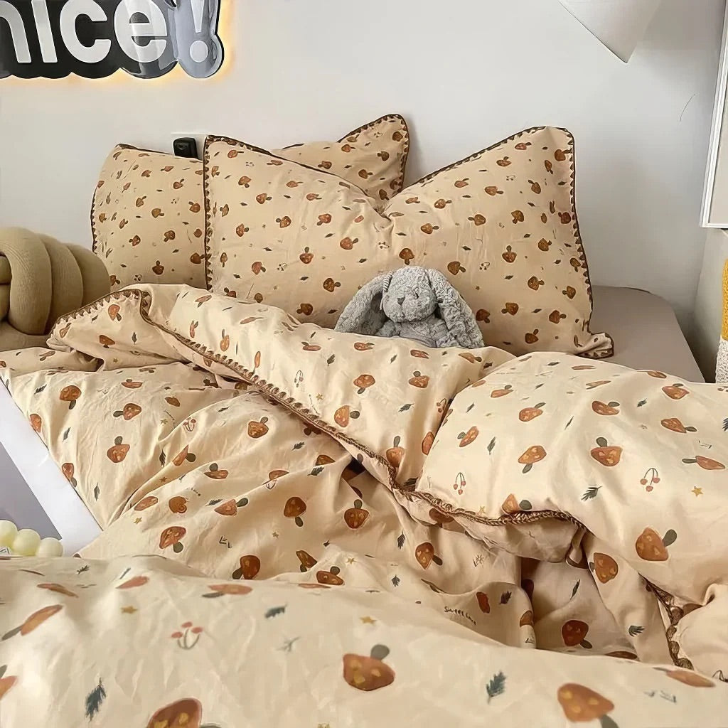 Beige bedding set with mushroom pattern on a bed, featuring pillows and a plush toy.