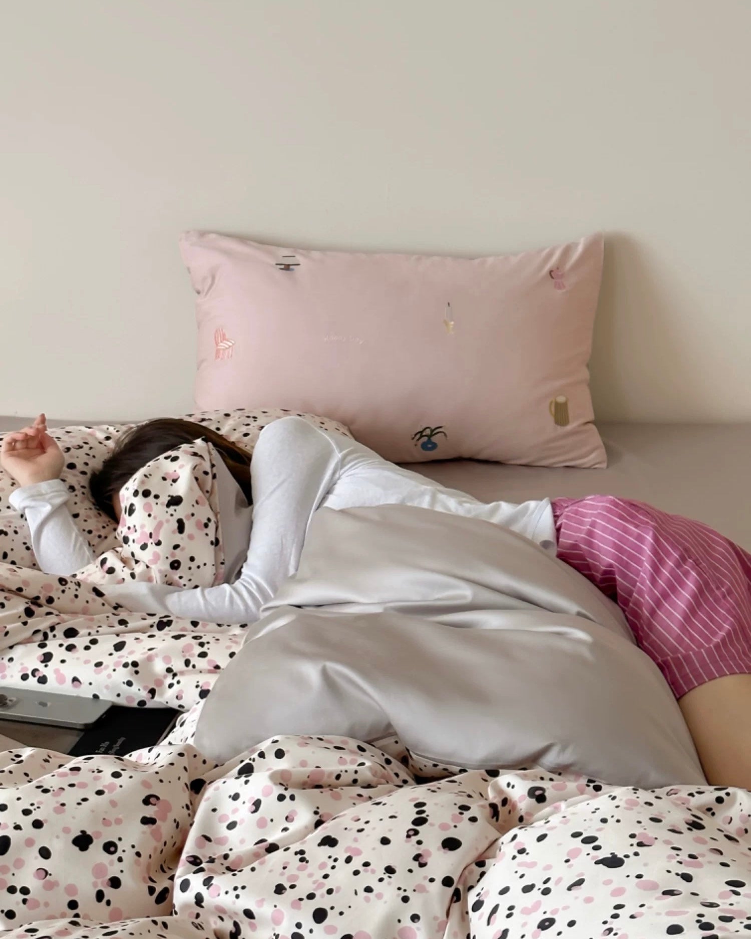 Person lying in bed with polka dot bedding and a pink pillow