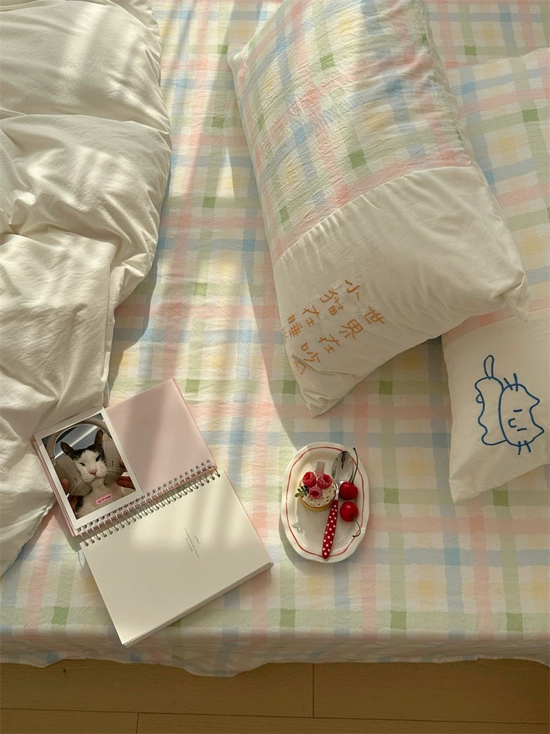 Pastel checkered bedspread with a notebook and small plate on a bed