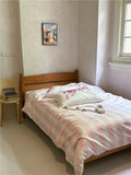Bedroom with a wooden bed and pink and white checkered blanket.