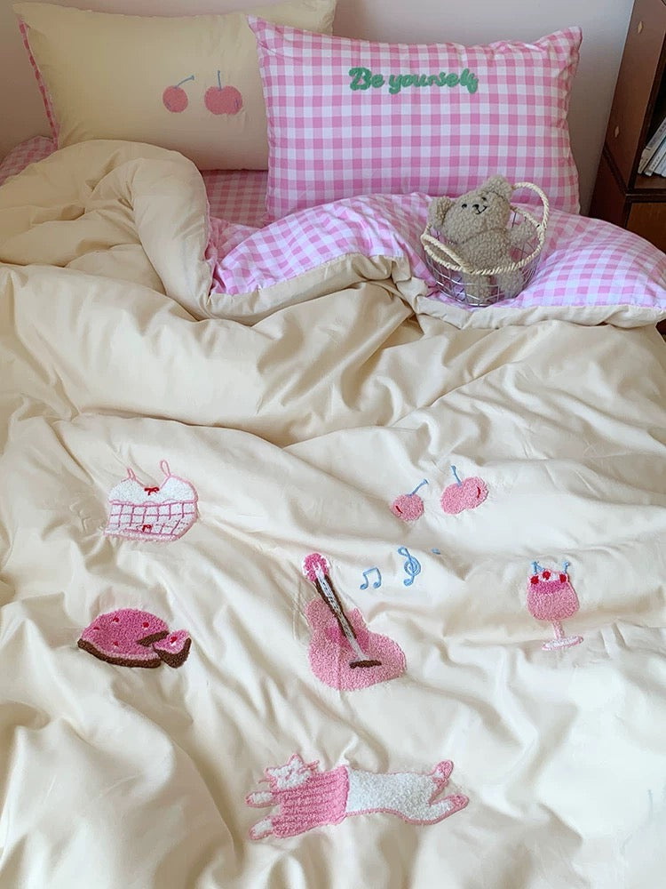 Bed with pink checkered pillow and decorative patches on a light-colored blanket.
