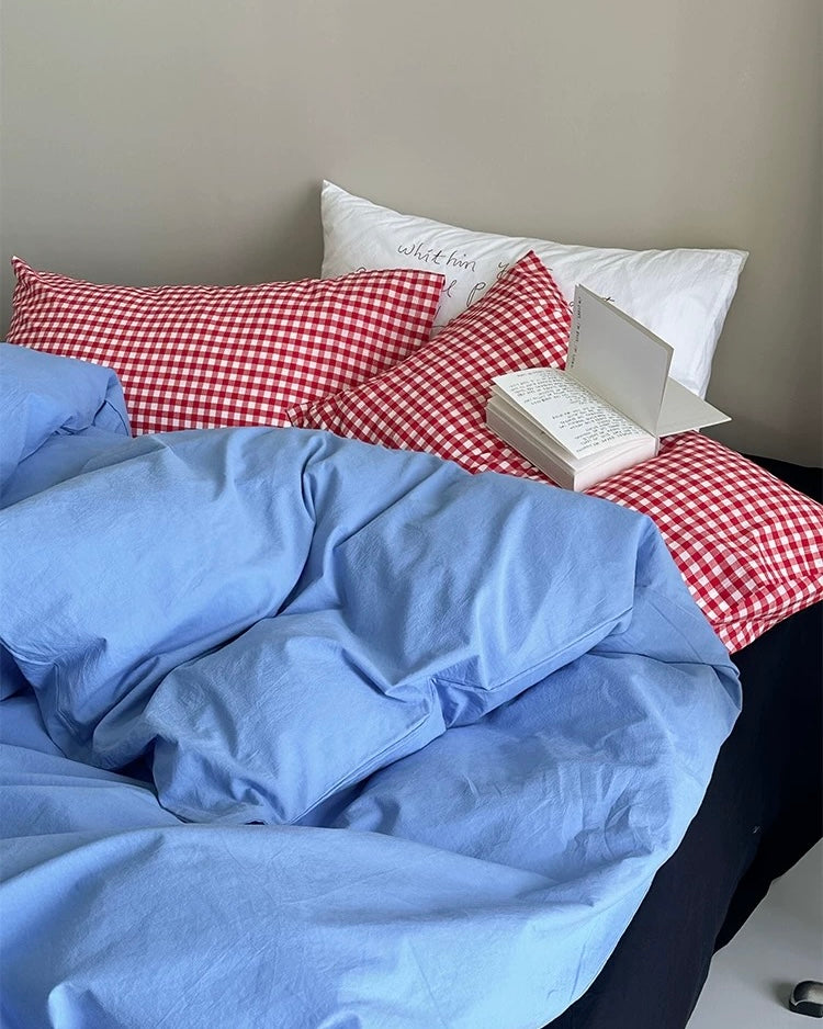 Preppy plaid pillows paired with blue cotton duvet in clean bedroom