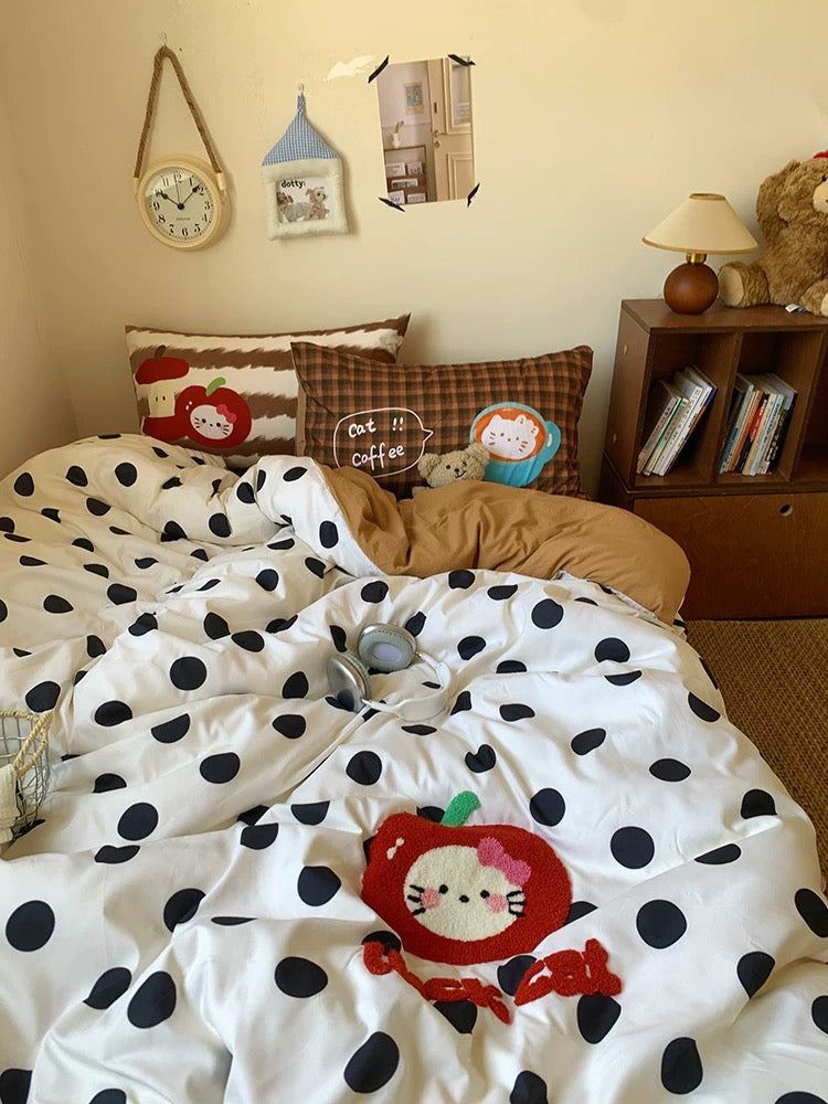 Children's bedroom with polka dot bedding featuring a Hello Kitty design, teddy bear, and books.