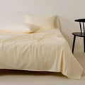 Beige bedspread with floral design on a bed against a white wall.