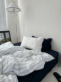 Bed with striped duvet and pillows in a bedroom setting