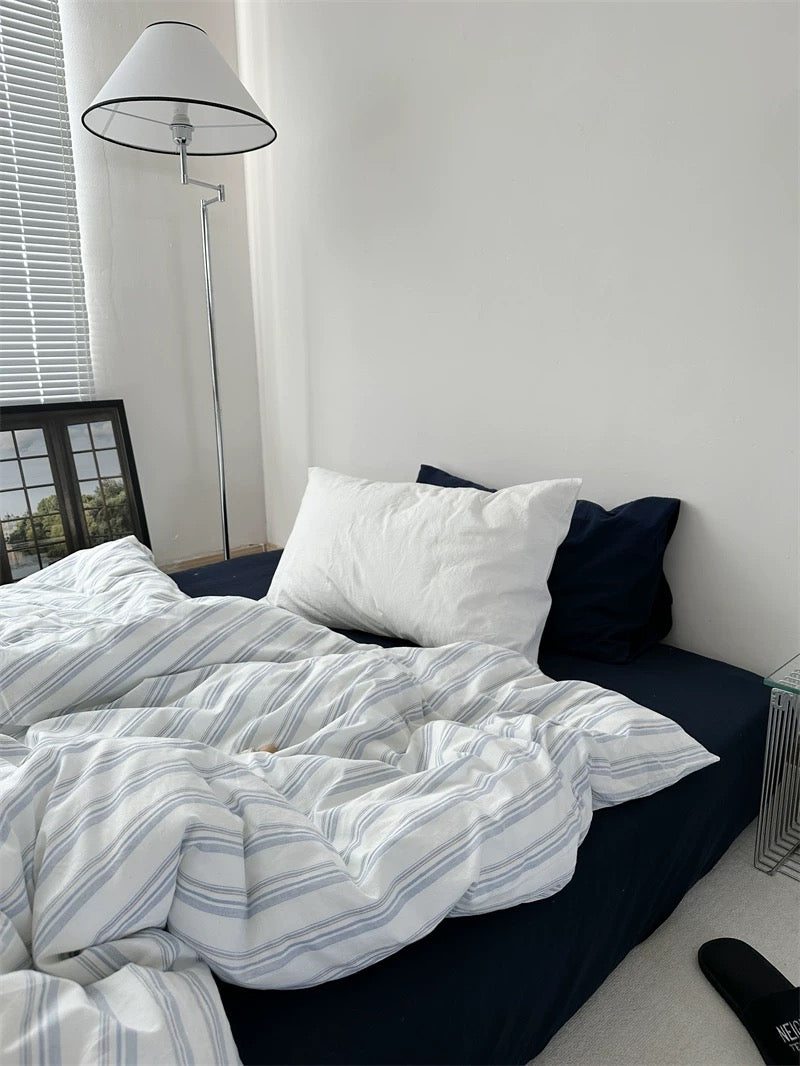 Bed with striped duvet and pillows in a bedroom setting
