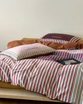 Striped bedding with pillows on a bed against a plain wall
