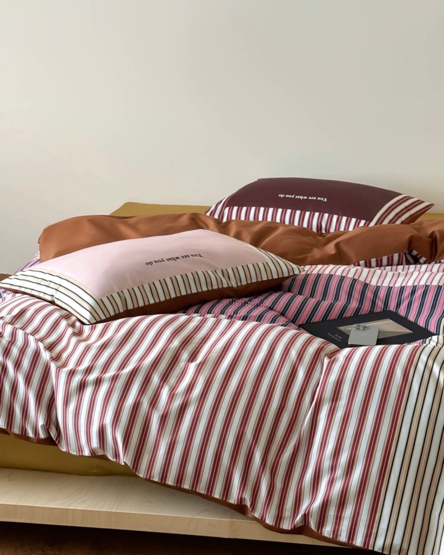 Striped bedding with pillows on a bed against a plain wall