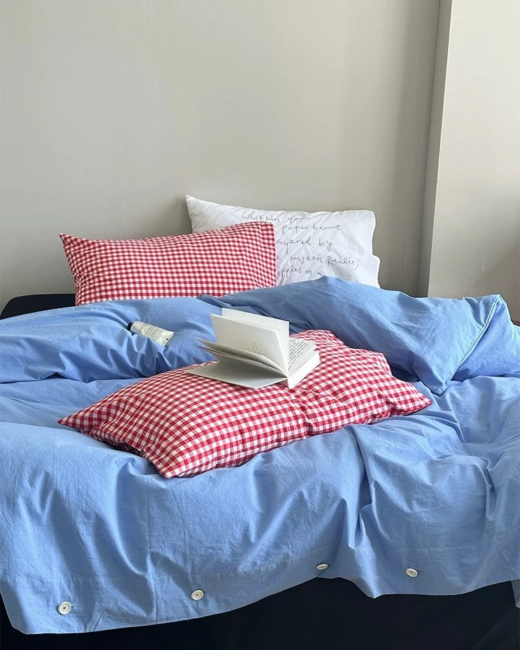 Cotton bedding set in blue with red plaid pillows on low bed
