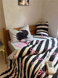 Bed with black and white striped bedding featuring pink bows, in a bedroom setting.
