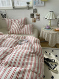 Striped bedding on a bed with a side table and decor in a room.