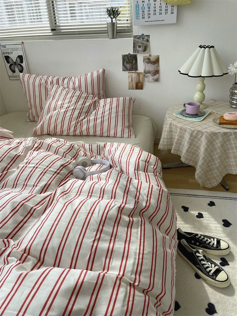 Striped bedding on a bed with a side table and decor in a room.