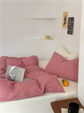Bed with red striped bedding, laptop, and orange on a white bed frame.