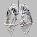 White outfit with black embroidery on a textured surface