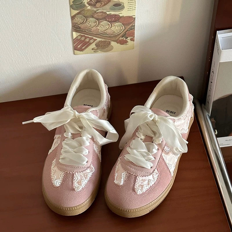 Pair of silver sneakers with white laces on a wooden surface.