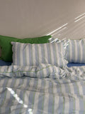 Striped bedding with a green pillow on a bed