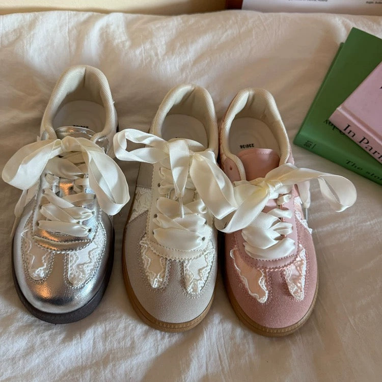 Three pairs of decorative sneakers on a bed with a book in the background.