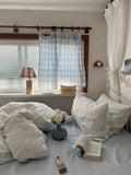 Cozy bedroom with a bed, pillows, and a window with curtains.