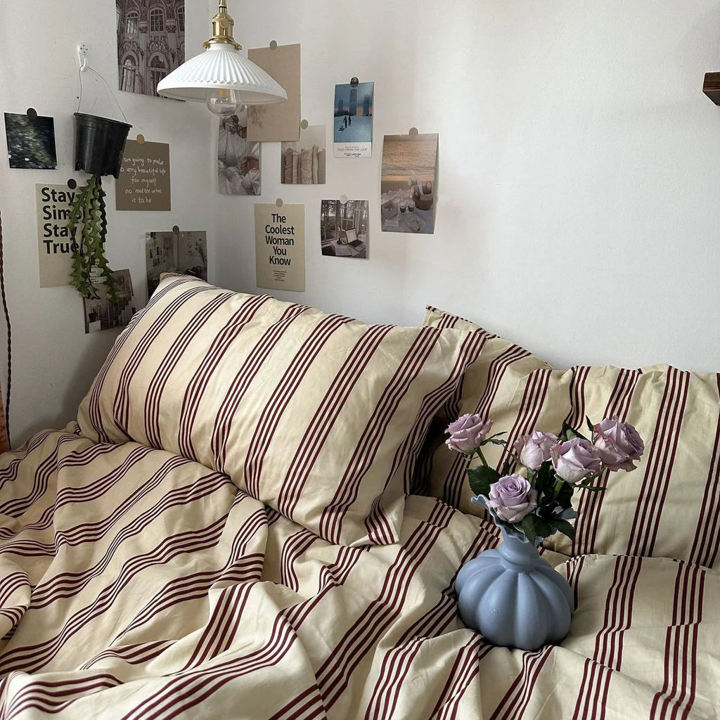 Striped blanket on a sofa with a vase and flowers, surrounded by wall art.