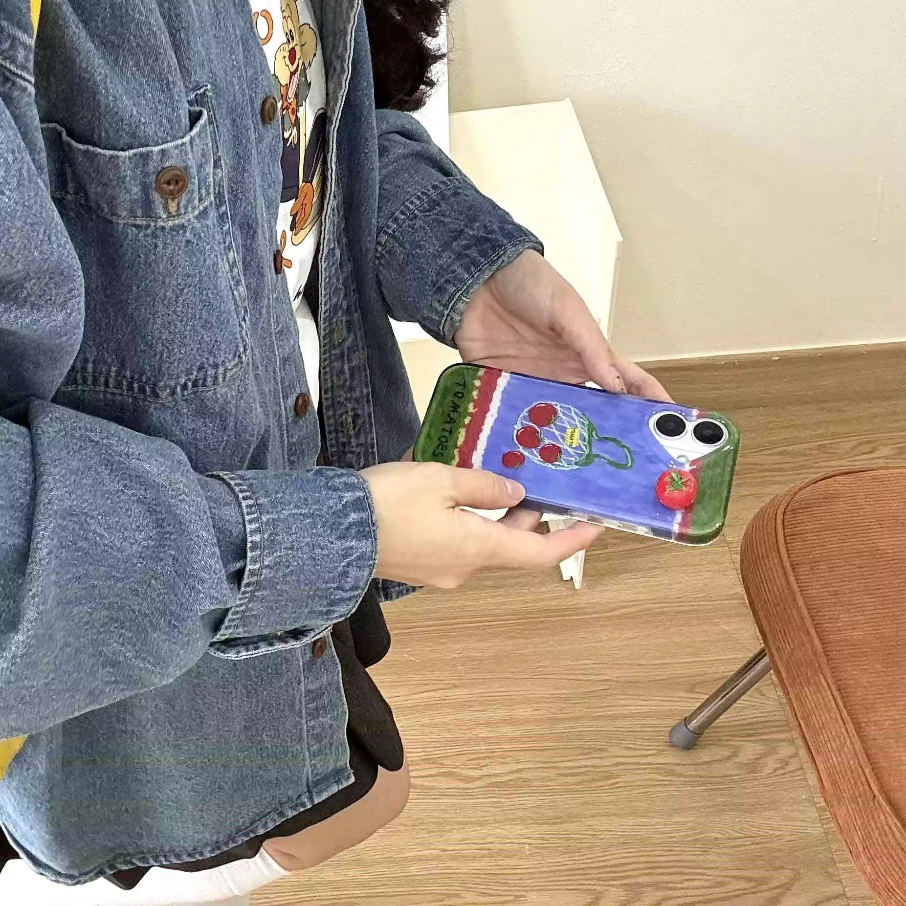 The iPhone case attached to a handbag via the chain, showcasing its portability