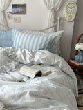 Bedroom with striped pillows and a book on a bed, clock on the wall.