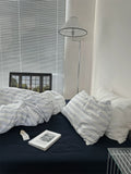 Bedroom with striped bedding, a book, and a lamp.