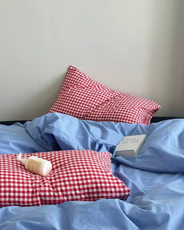 Simple college room bed styled with blue cotton bedding and red checks