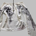 White long-sleeve shirt with black intricate designs on a textured surface