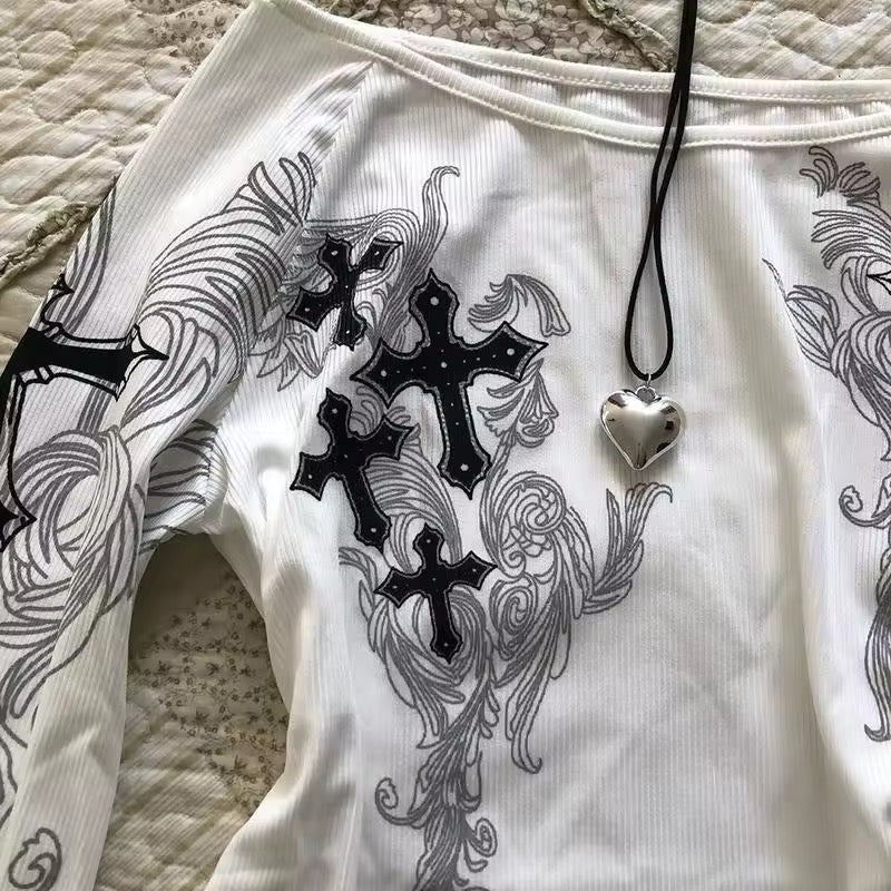 White garment with black cross designs and a heart-shaped pendant on a textured surface