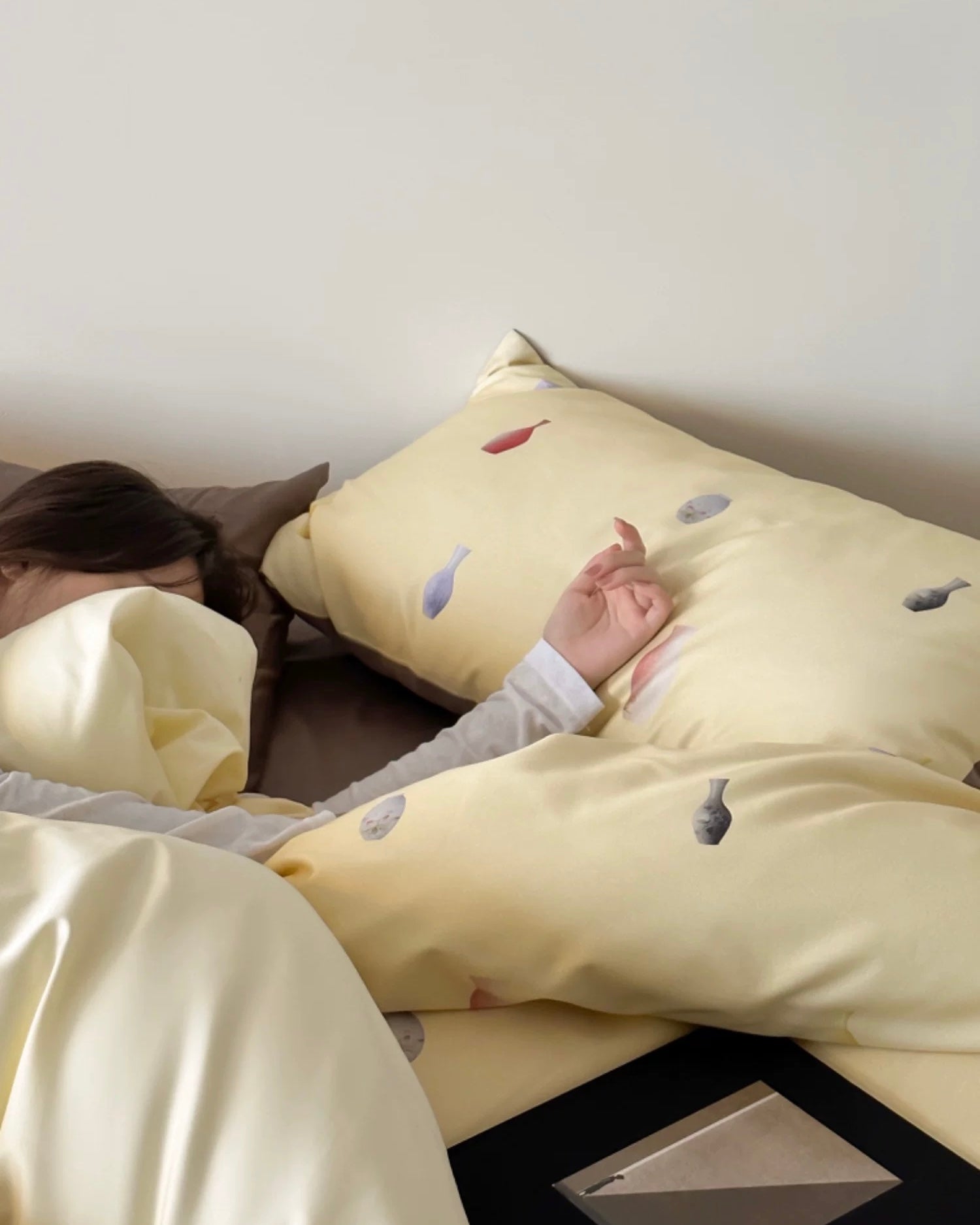 Person lying in bed with a yellow pillow featuring embroidered designs.